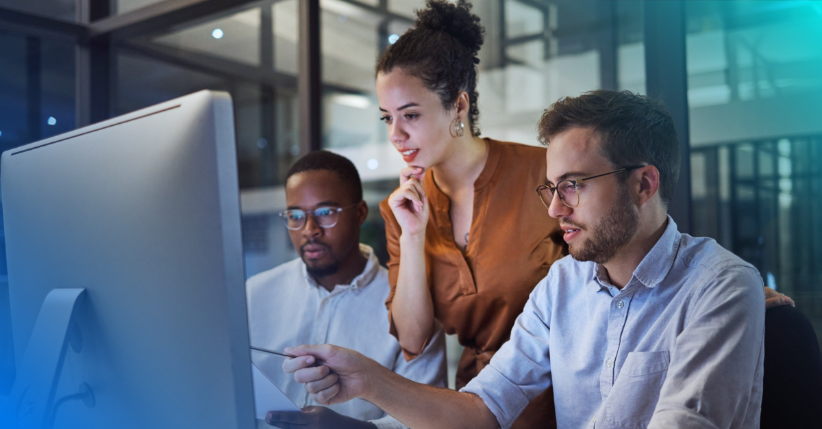 Three people around a computer monitor 