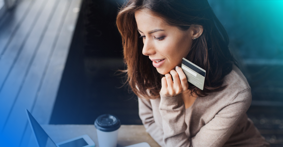 Woman holds credit card while sitting in front of her laptop.