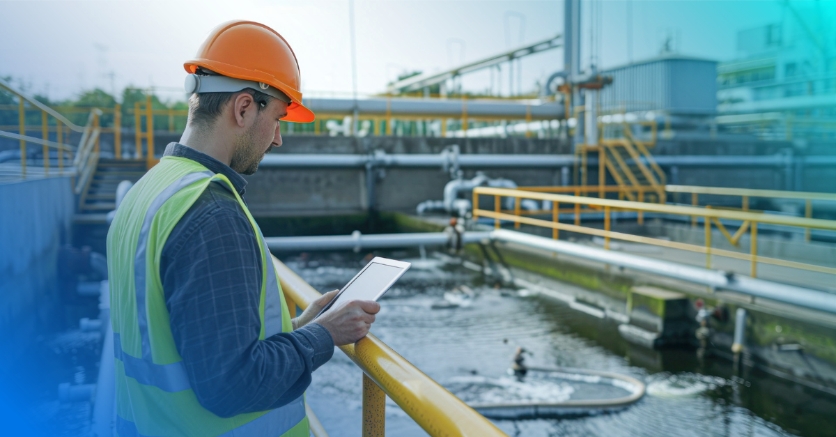 Utility worker reading tablet at water treatment plant. 