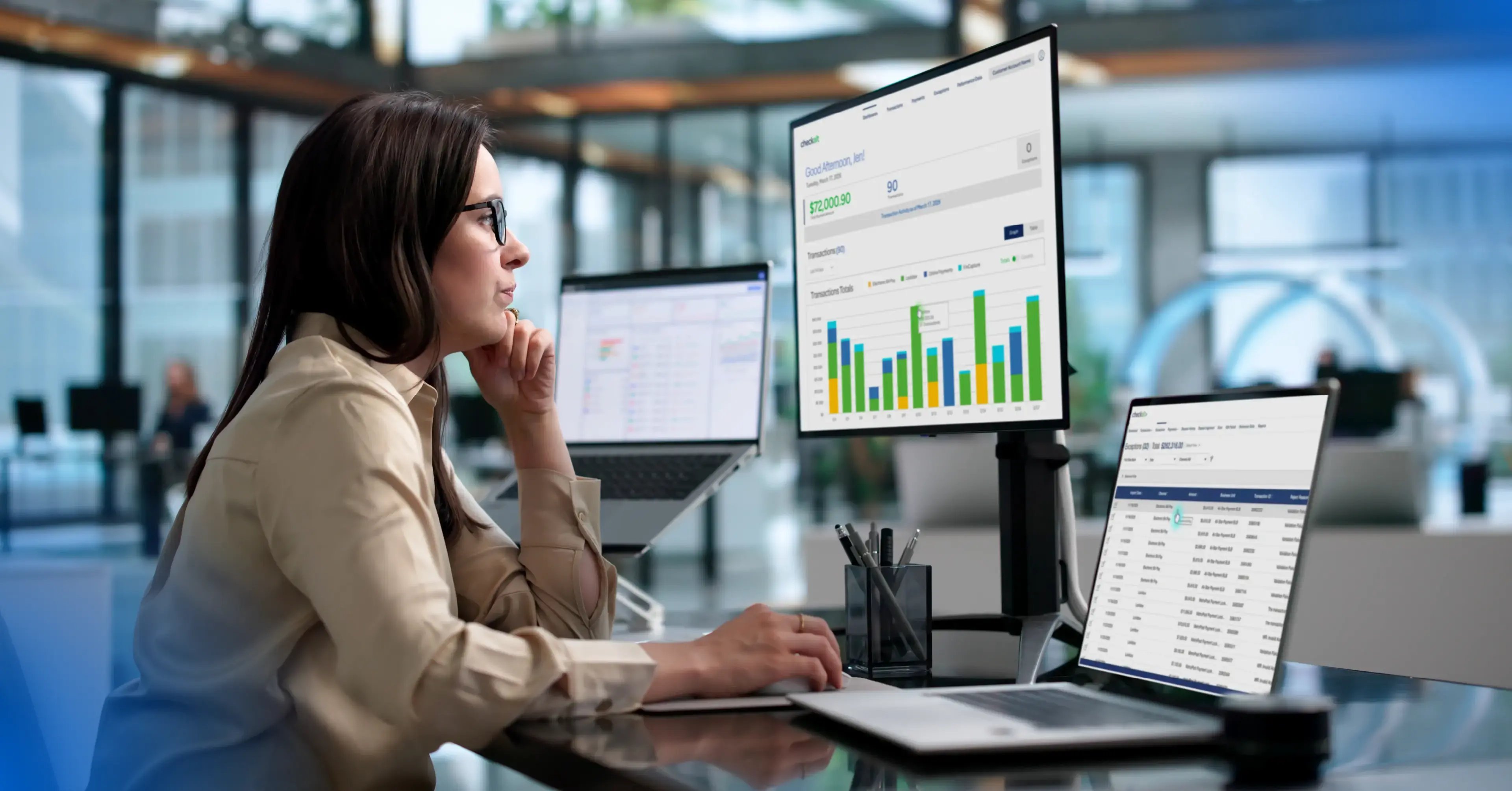 Young woman working at a desk with three monitors.